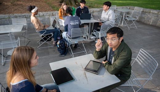 Several undergraduate students study and talk around outdoor tables on campus near Harrison Square in Atlanta, Georgia.