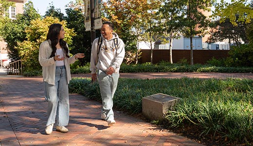Two Tech Promise students walk down a brick pathway through greenery on Georgia Tech’s Atlanta campus.