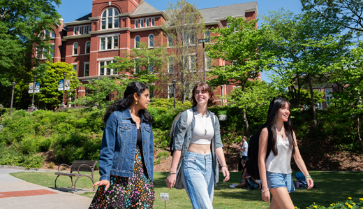 Three undergraduate students walk on the pathway beneath Georgia Tech’s iconic Tech Tower.